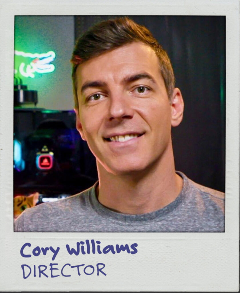 A portrait of a white man with short brown hair and a grey t-shirt. The text below reads: Cory Williams. Director.