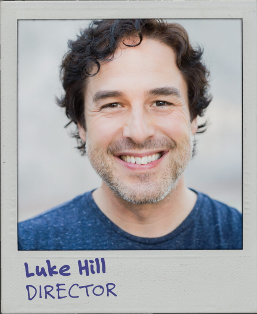 A portrait of a white man with curly brown hair. The text below reads: Luke Hill. Director