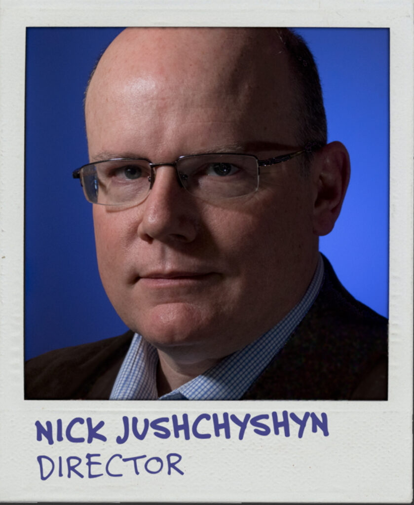 Portrait of a white man with a bald head, glasses, and a blue background. The text below reads: Nick Jushchyshyn. Director.